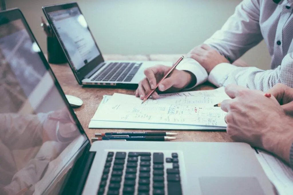 What Is A Dividend Aristocrat? Learn 5 Secrets To Safe Investing Today! 2 Person Holding Pencil Near Laptop Computer - What Is A Dividend Aristocrat