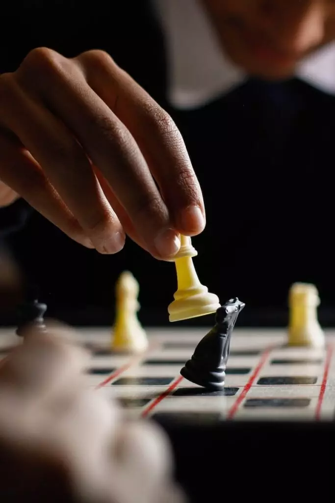 Person Holding White Chess Piece; Dividend Investing Vs Growth