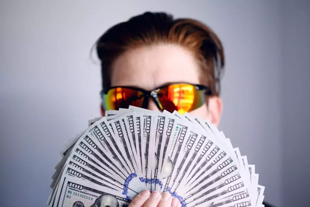 Man In Black Framed Sunglasses Holding Fan Of White And Gray Striped Cards; Dividend Investing For Income