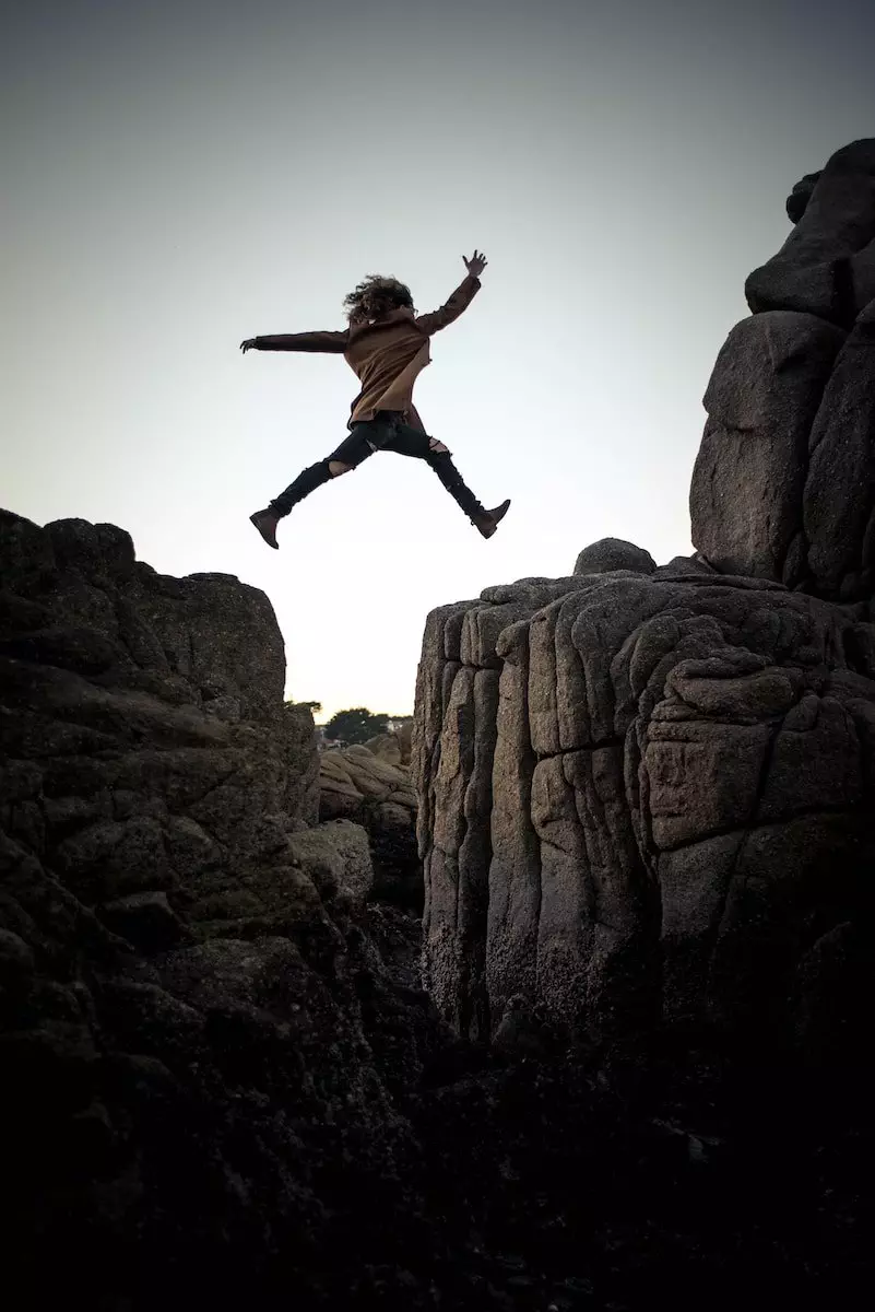 person jumping on big rock under gray and white sky during daytime; High Yields Signal Impending Doom; dividend investing