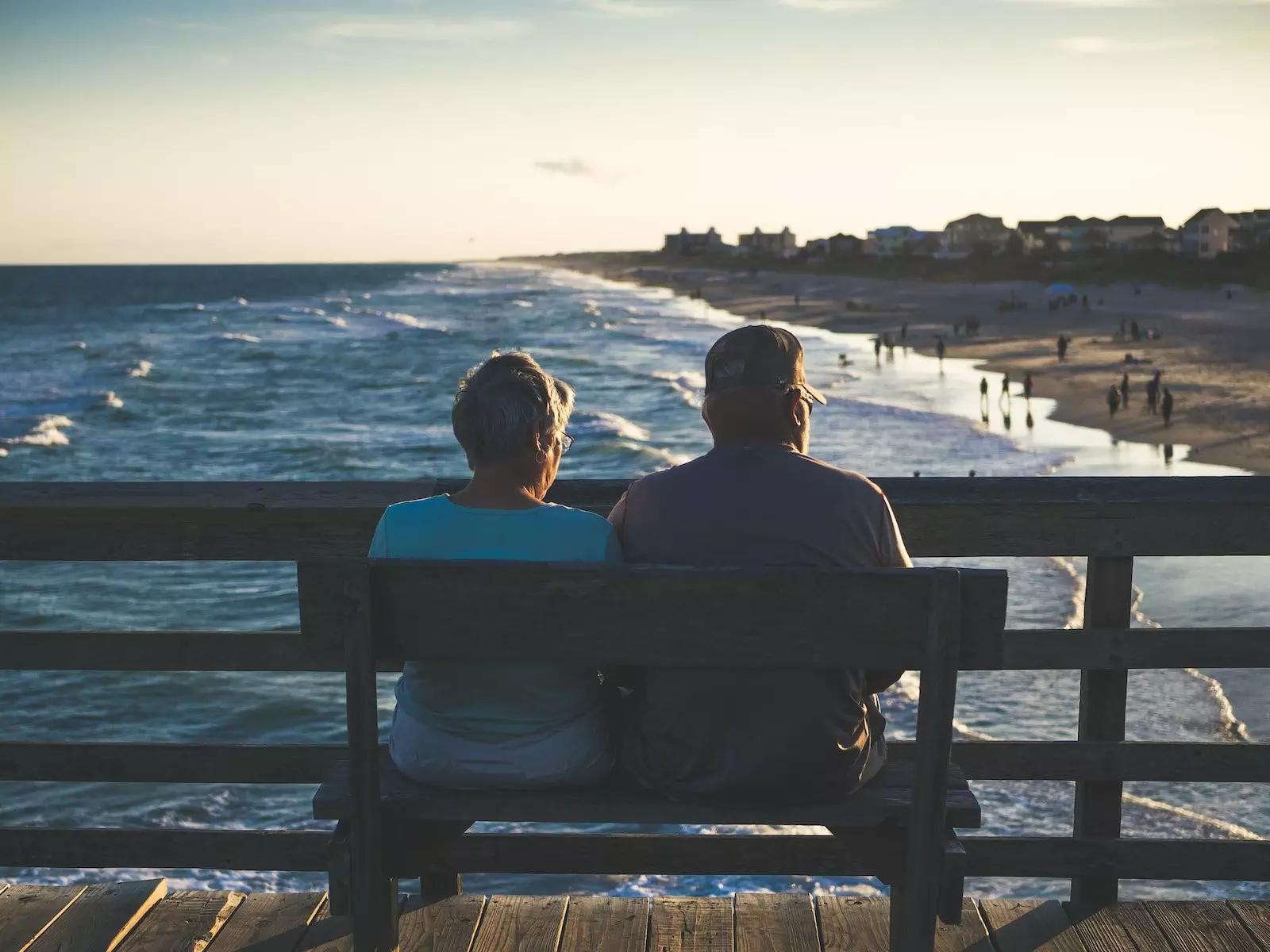 man and woman sitting on bench in front of beach; are dividend stocks best for retirement